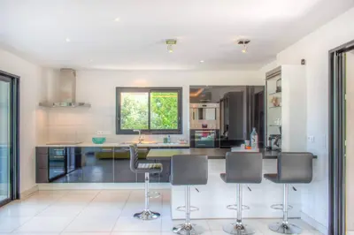 a kitchen with a counter with chairs and a window at alba in Pinarellu