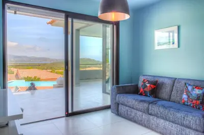 a living room with a couch and a sliding glass door at alba in Pinarellu