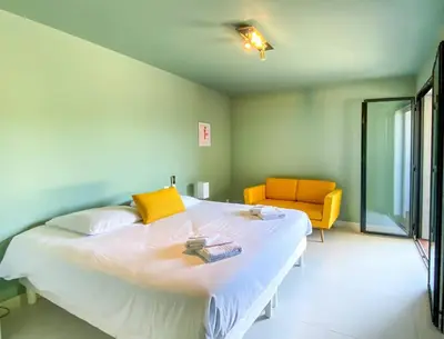 a bedroom with a large bed and a yellow chair at alba in Pinarellu
