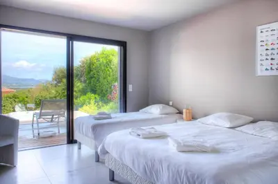 two beds in a room with a large window at alba in Pinarellu