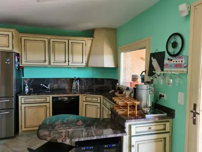 a kitchen with green walls and wooden cabinets at la grande piscine in Porto-Vecchio