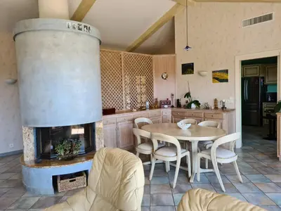a kitchen with a fireplace and a table and chairs at la grande piscine in Porto-Vecchio