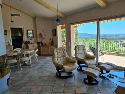 a living room with two chairs and a balcony at la grande piscine in Porto-Vecchio