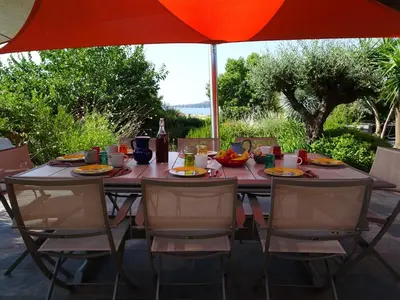 a dining table with chairs and an umbrella at Les Voiles in Pinarellu