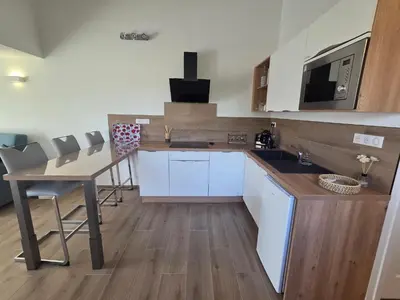 a kitchen with white cabinets and a table and chairs at Agréable T2 proche Porto Vecchio in Sotta