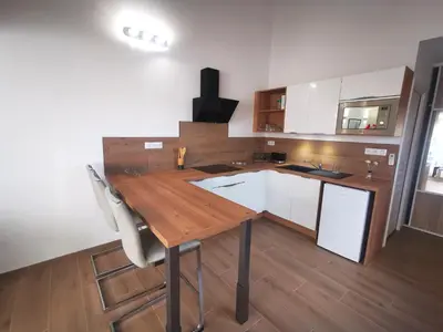 a kitchen with a wooden table and white cabinets at Agréable T2 proche Porto Vecchio in Sotta