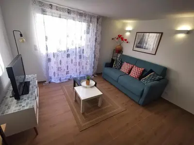 a living room with a blue couch and a table at Agréable T2 proche Porto Vecchio in Sotta