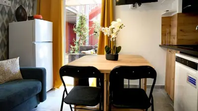 a small kitchen with a table with chairs and a refrigerator at T2 Cyprien, Climatisé, piscines, resto, Plages 2-4 pers in Lecci