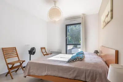 a bedroom with a bed with a chair and a window at La Plage d'Argent - Vue mer et montagne in Coti-Chiavari