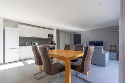 a kitchen and dining room with a wooden table and chairs at La Plage d'Argent - Vue mer et montagne in Coti-Chiavari