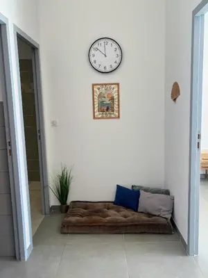 a clock on a white wall above a couch at Bel appartement avec piscine en bord de mer in Ajaccio