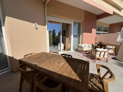 a wooden table and chairs on a patio at Bel appartement avec piscine en bord de mer in Ajaccio