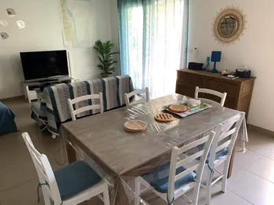 a dining table and chairs in a living room at Accès Direct Mer, Commerces Rivière 15mn in Santa-Lucia-di-Moriani