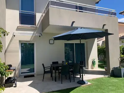 a patio with a table and an umbrella at Accès Direct Mer, Commerces Rivière 15mn in Santa-Lucia-di-Moriani