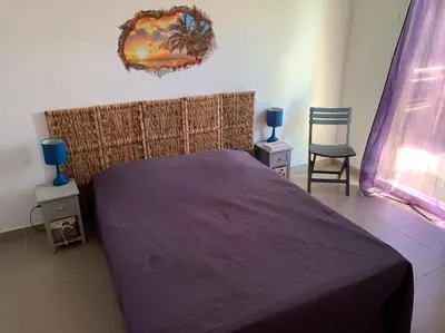 a bedroom with a purple bed and two chairs at Accès Direct Mer, Commerces Rivière 15mn in Santa-Lucia-di-Moriani