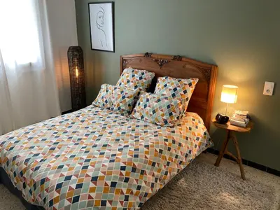 a bed with a colorful comforter and a side table at Location appartement de vacances Ajaccio in Ajaccio