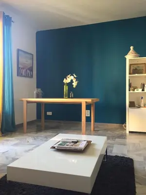 a living room with a table and a blue wall at Location appartement de vacances Ajaccio in Ajaccio