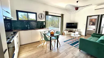 a kitchen and living room with a table and a couch at havre de paix à Pianottoli proche des plages in Pianottoli-Caldarello