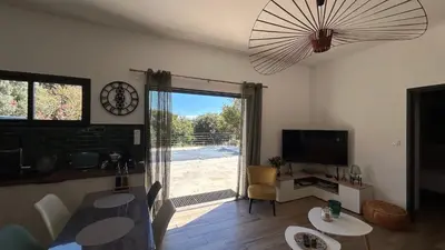 a living room with a table and a clock on the wall at havre de paix à Pianottoli proche des plages in Pianottoli-Caldarello