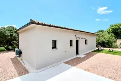 a white building with black windows on the side of it at havre de paix à Pianottoli proche des plages in Pianottoli-Caldarello