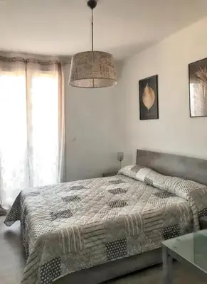 a bedroom with a bed and a chandelier at Appartement à Ajaccio avec vue sur la mer in Ajaccio