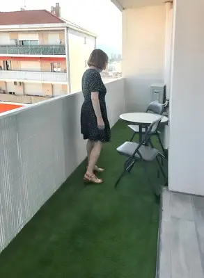 a woman standing on a balcony with green flooring at Appartement à Ajaccio avec vue sur la mer in Ajaccio