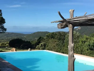 a blue swimming pool with a view of the ocean at Gîte Ortolu in Monacia-dʼAullène