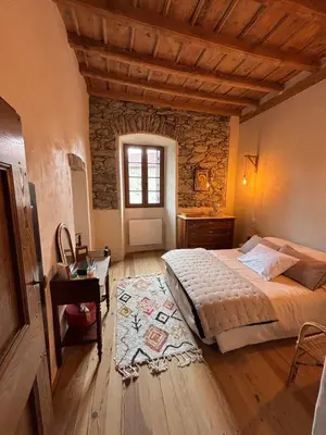 a bedroom with a bed and a table and a window at Maison de Caractère au coeur du village in Castifao