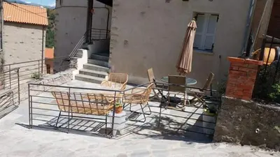 a patio with chairs and a table and an umbrella at Maison de Caractère au coeur du village in Castifao