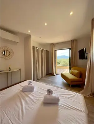 a bedroom with a bed and a couch and a window at Maison chaleureuse accès privé à la plage in Olmeto