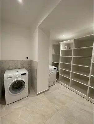 a laundry room with a washing machine and shelves at Maison chaleureuse accès privé à la plage in Olmeto