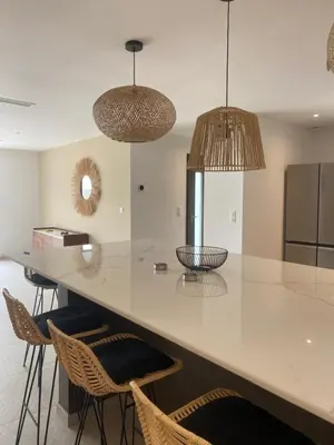 a kitchen with a counter with chairs and pendant lights at Maison chaleureuse accès privé à la plage in Olmeto