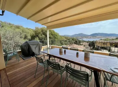 a wooden deck with a table and chairs on it at Maison chaleureuse accès privé à la plage in Olmeto