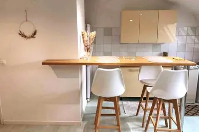a kitchen with a wooden table and white stools at Loft Place du Diamant Hyper centre ville Plage 50m in Ajaccio