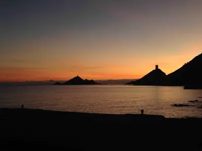 a sunset over a body of water with a lighthouse at Loft Place du Diamant Hyper centre ville Plage 50m in Ajaccio