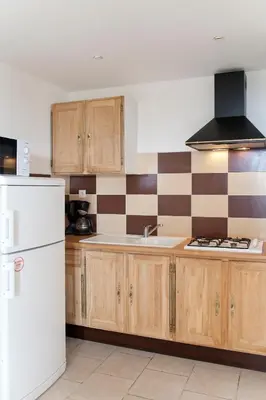 a kitchen with wooden cabinets and a white refrigerator at Le Thyreneen in Sari Solenzara
