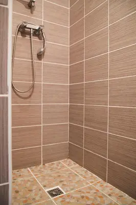 a bathroom with a shower with brown tiles at Le Thyreneen in Sari Solenzara