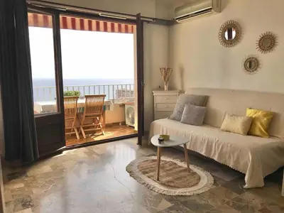 a living room with a couch and a table and a balcony at Helios grand studio terrasse panoramique magique in Ajaccio