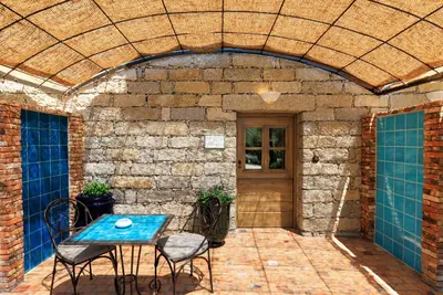 a patio with a table and chairs and a brick wall at A Mandria di Murtoli in Sartène