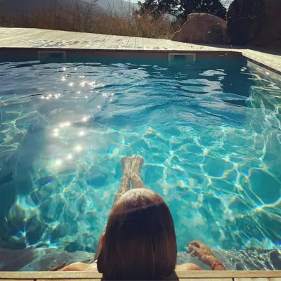 a woman sitting in front of a swimming pool at Stone Sheepfold With Sea View In Corsica in Sari-dʼOrcino