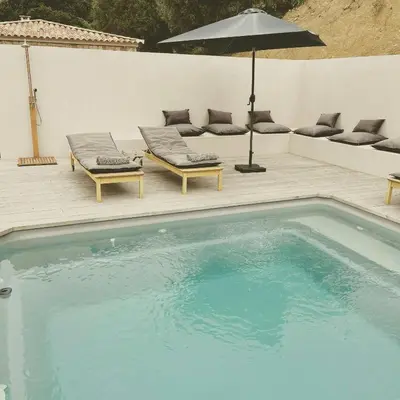 a swimming pool with two lounge chairs and an umbrella at Stone Sheepfold With Sea View In Corsica in Sari-dʼOrcino