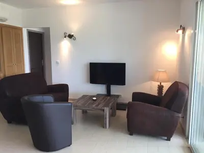 a living room with two chairs and a flat screen tv at Locations I Carboni - villa 2 chambres in Sollacaro