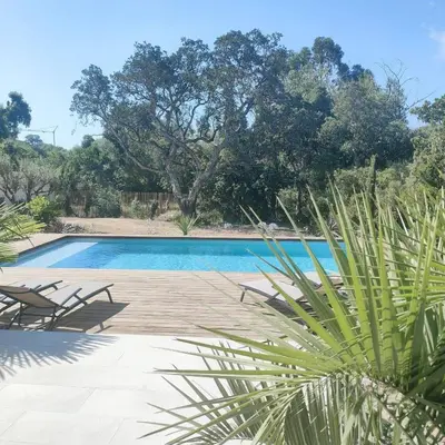 a pool with chairs and trees in the background at suara in Pinarellu
