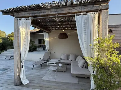 a pergola with a couch and a table on a patio at suara in Pinarellu