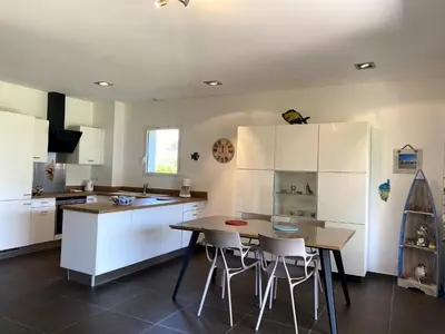 a kitchen with white cabinets and a table and chairs at t3cj n14 in Pinarellu