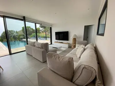 a living room with a large flat screen tv and chairs at Rostalana in Pinarellu