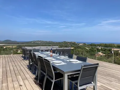 a dining table and chairs on a wooden deck at Rostalana in Pinarellu