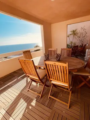 a dining room with a table and chairs and the ocean at Ajaccio sanguinaires F3 in Ajaccio