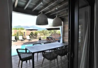 a dining room with a table and chairs and a pool at alcudina in Zonza