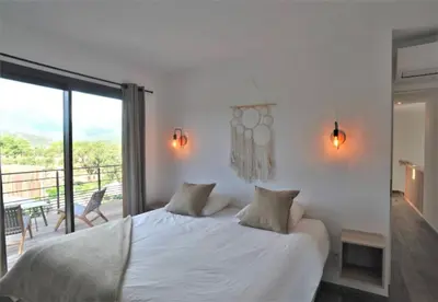 a bedroom with a white bed and a balcony at alcudina in Zonza